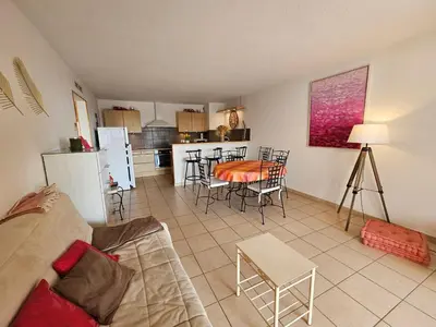 a living room and kitchen with a couch and a table at Palmeraie 130- vue mer et village- plage et commerces à pieds in Sari Solenzara