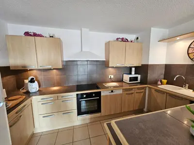 a kitchen with wooden cabinets and a microwave at Palmeraie 130- vue mer et village- plage et commerces à pieds in Sari Solenzara