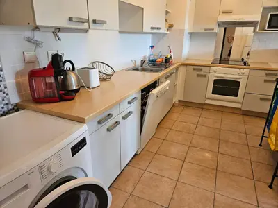 a kitchen with white cabinets and a washer and dryer at Palmeraie 406- vue piscine- clim- proche plage et commerces in Sari Solenzara