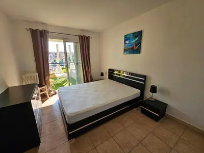 a bedroom with a bed and a balcony at Palmeraie 406- vue piscine- clim- proche plage et commerces in Sari Solenzara