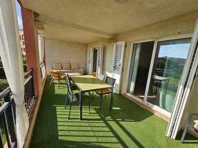 a patio with a table and chairs on a balcony at Palmeraie 406- vue piscine- clim- proche plage et commerces in Sari Solenzara