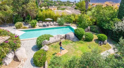 a woman is standing in a garden near a swimming pool at Magnifique Villa de Luxe avec Piscine in Porto-Vecchio