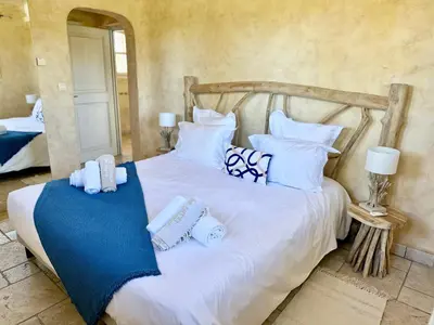 a bedroom with a white bed with blue and white pillows at Magnifique Villa de Luxe avec Piscine in Porto-Vecchio
