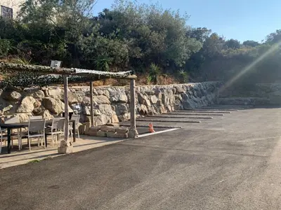 a table and chairs next to a stone wall at Grand T4 , vue magnifique à 50 m de la plage in Propriano