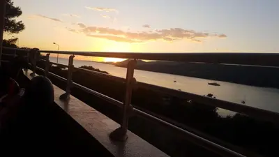 a person sitting on a fence watching the sunset at Grand T4 , vue magnifique à 50 m de la plage in Propriano