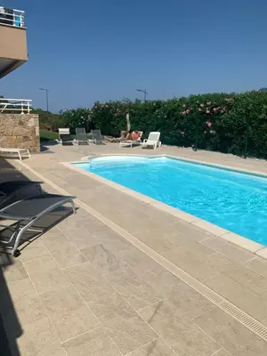 a swimming pool with chairs and a person sitting next to it at Grand T4 , vue magnifique à 50 m de la plage in Propriano