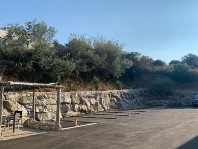 a parking lot with a stone wall and a table and chairs at Grand T4 , vue magnifique à 50 m de la plage in Propriano
