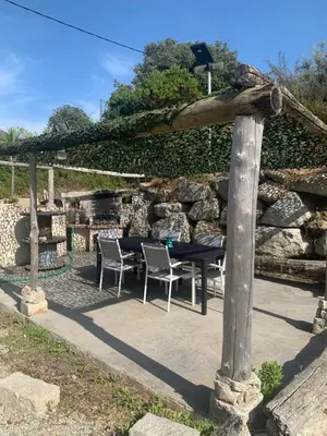 a patio with a table and chairs and a stone wall at Grand T4 , vue magnifique à 50 m de la plage in Propriano
