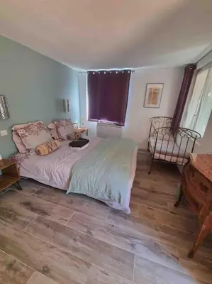 a bedroom with a bed and a chair and a table at Rez de chaussée villa avec piscine in Piana