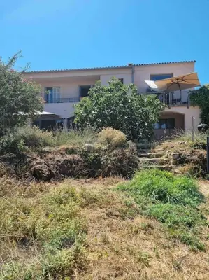 a building with an umbrella in a field of grass at Rez de chaussée villa avec piscine in Piana