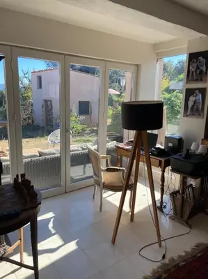 a living room with a table and a desk with a chair at Rez de chaussée villa avec piscine in Piana