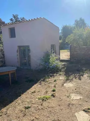 a small white house with a bench in front of it at Rez de chaussée villa avec piscine in Piana