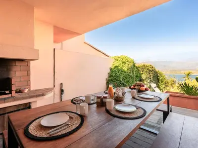 a wooden table with plates on it on a balcony at Holiday Home Verde by Interhome in Porto-Vecchio