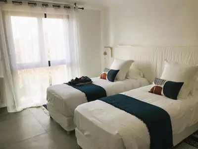 two beds in a white room with a window at Villa Arazu, 10 personnes, piscine chauffée, vue mer, 15 minutes à pieds plage in Cirendinu