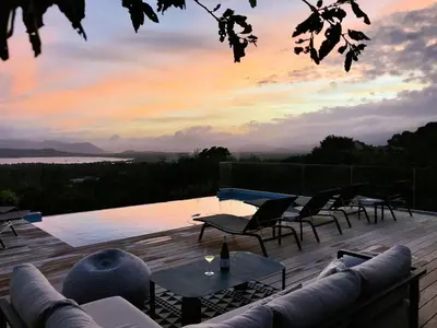 a deck with chairs and tables and a view of the water at Villa Arazu, 10 personnes, piscine chauffée, vue mer, 15 minutes à pieds plage in Cirendinu