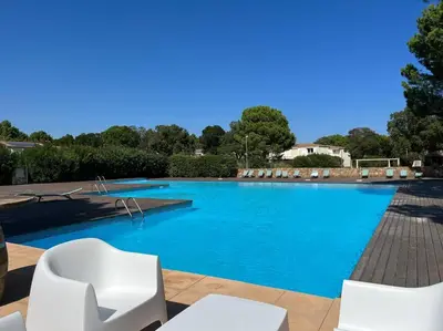 a large swimming pool with white chairs and blue water at Havre de paix Fiori di Cala Rossa in Lecci