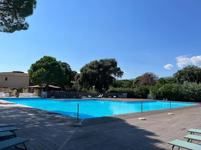 a large blue swimming pool with chairs and trees at Havre de paix Fiori di Cala Rossa in Lecci