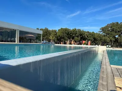 a swimming pool with blue water in front of a building at Mini villa T3 de 48m2 in Lecci