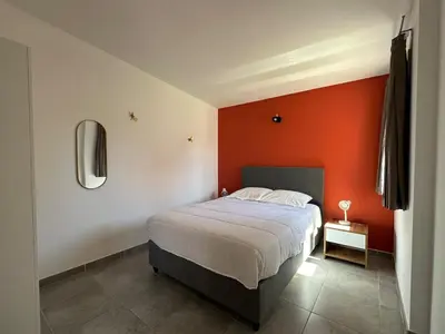 a bedroom with a bed and an orange wall at Mini villa T3 de 48m2 in Lecci