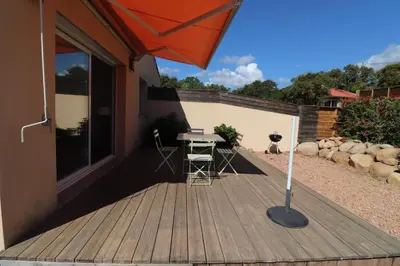 a wooden deck with a table and an umbrella at Accommodation Close To Pinarello Beach in Conca