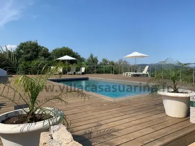a wooden deck with two potted plants and a swimming pool at Villa vue mer, piscine chauffée à Porto Vecchio in Porto-Vecchio