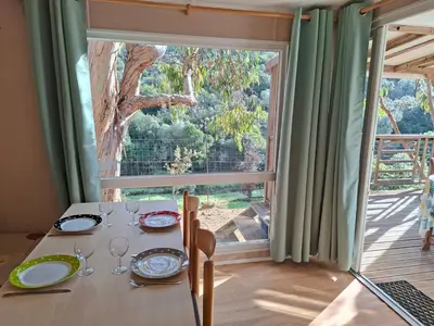 a dining table with a view of a large window at Mira Monti Location in Belvédère