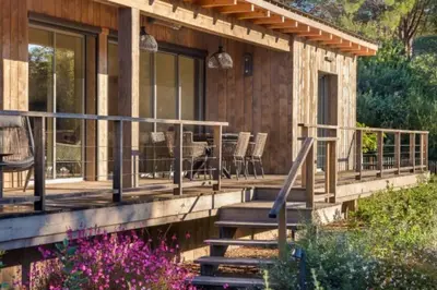 a house with a deck with chairs and a table at Lodge Les Oliviers Di Lecci in Lecci
