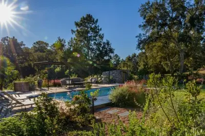 a swimming pool in a garden with the sun in the sky at Lodge Les Oliviers Di Lecci in Lecci