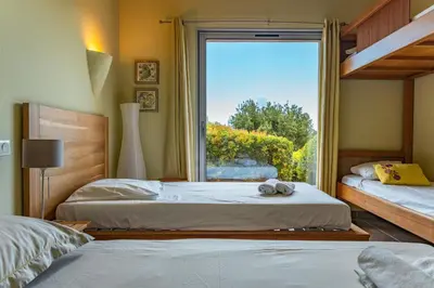 two beds in a room with a window at Villa Pina in Sainte-Lucie de Porto-Vecchio