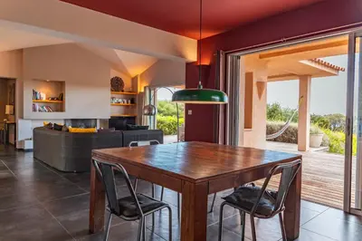 a kitchen and living room with a wooden table and chairs at Villa Pina in Sainte-Lucie de Porto-Vecchio