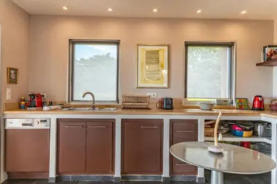 a kitchen with a sink and a table and two windows at Villa Pina in Sainte-Lucie de Porto-Vecchio