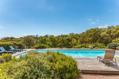 a swimming pool with a wooden deck and chairs next to it at Villa Pina in Sainte-Lucie de Porto-Vecchio