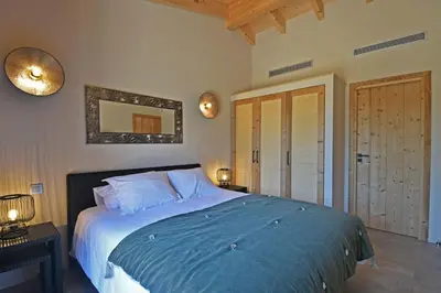 a bedroom with a bed with blue sheets and a mirror at Lodge La Myrte Di Lecci in Lecci