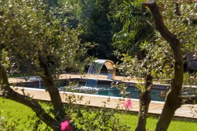 a swimming pool with a water fountain in a yard at Lodge Les Arbousiers Di Lecci in Lecci