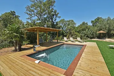 a swimming pool with a wooden deck and a pergola at Lodge Les Arbousiers Di Lecci in Lecci