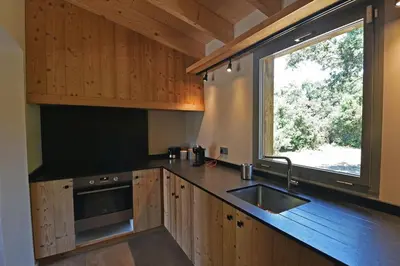 a kitchen with wooden cabinets and a sink and a window at Lodge Les Arbousiers Di Lecci in Lecci