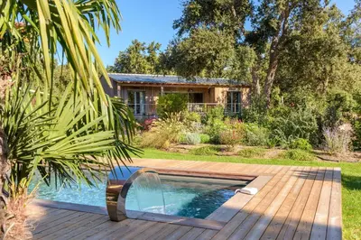 a swimming pool in a garden with a house at Lodge Les Arbousiers Di Lecci in Lecci