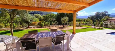 a wooden table and chairs on a patio with a view at Villa Florida, 8 pers, vue montagne, 350 m plage à pieds in Pinarellu
