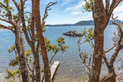 a rock in the water with trees in the foreground at Villa A signoria in Porto-Vecchio