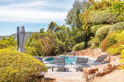 a pool with chaise lounge chairs next to a garden at Villa A signoria in Porto-Vecchio