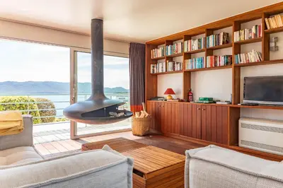 a living room with a fireplace and a large window at Villa A signoria in Porto-Vecchio