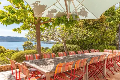 a wooden table with chairs and an umbrella at Villa A signoria in Porto-Vecchio