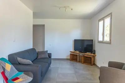 a living room with a couch and a flat screen tv at Casetta Taglio Rosso Di Santa Lucia in Sainte-Lucie de Porto-Vecchio