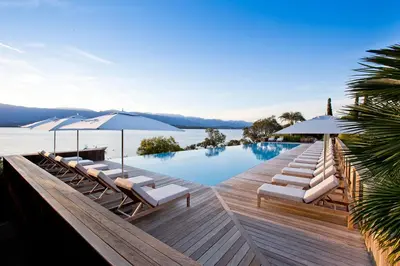 a pool with chairs and umbrellas on a wooden deck at Casadelmar in Porto-Vecchio