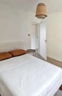 a large white bed in a white room with a lamp at Appartement spacieux à Cargèse avec terrasse vue mer in Cargèse