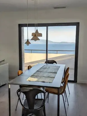 a dining room with a table and a view of the ocean at Appartement spacieux à Cargèse avec terrasse vue mer in Cargèse