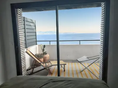 a bedroom with a balcony with a view of the ocean at Appartement spacieux à Cargèse avec terrasse vue mer in Cargèse