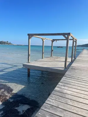 a wooden pier with a bench on the beach at Appartement meublé Porto vecchio in Porto-Vecchio