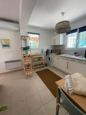 a kitchen with white cabinets and a table and a sink at Appartement meublé Porto vecchio in Porto-Vecchio