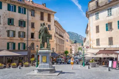 a woman walking down a street with a statue at Corte tres beau T2 neuf hyper centre 4 personnes calme et lumineux wifi lave linge in Corte